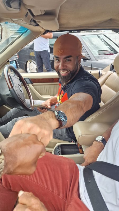 Fist bumping with car driver in Mercedes-Benz car.